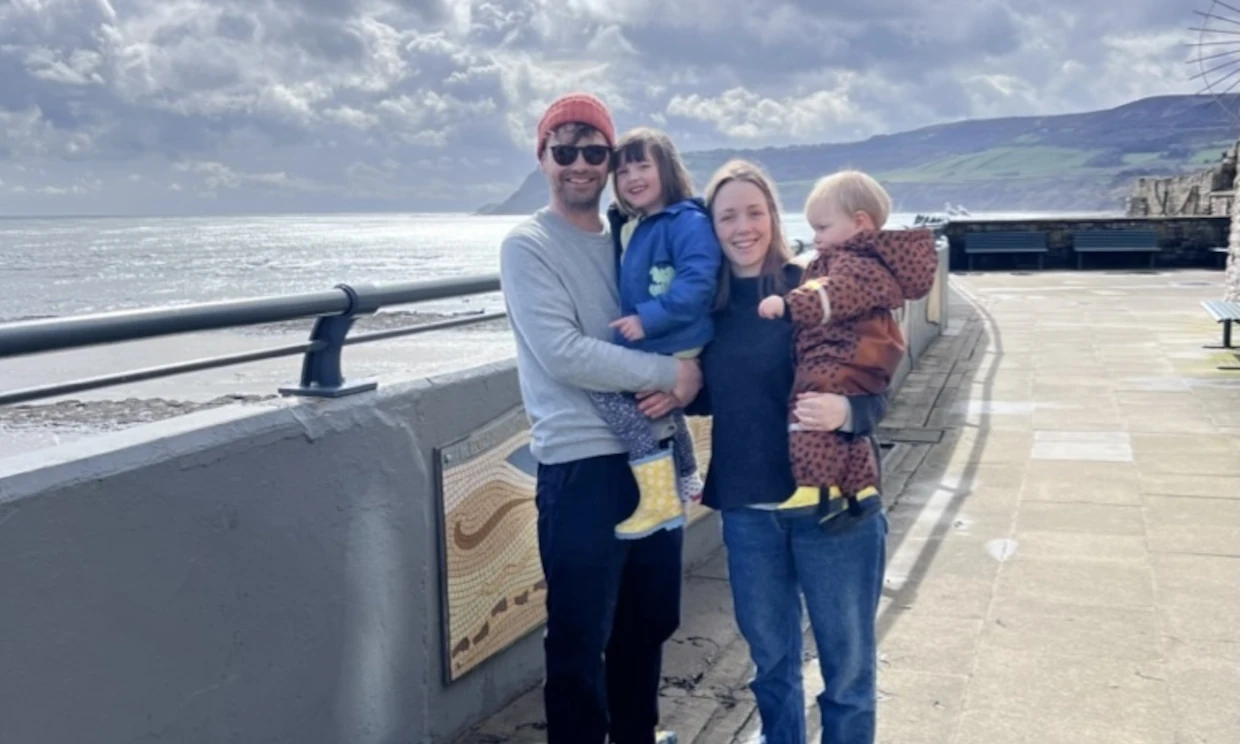 Two adults and their small children smiling by the sea