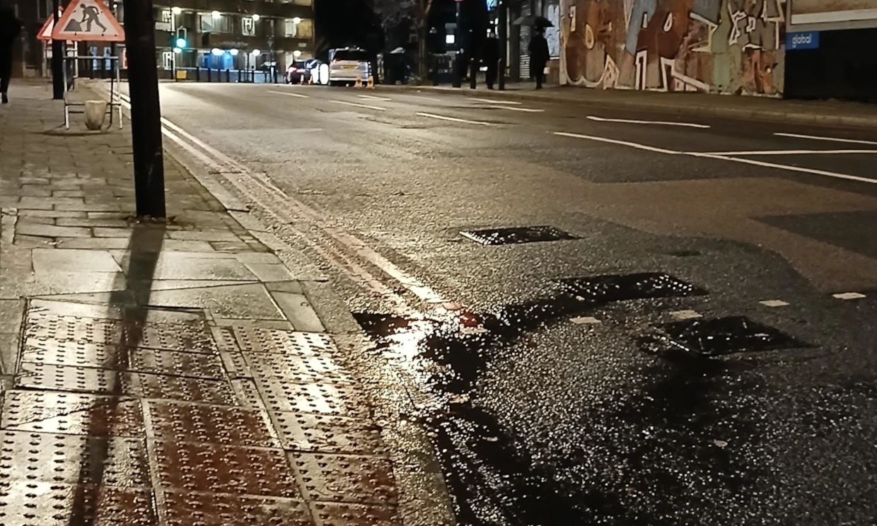 A manhole cover leaks water down a street.