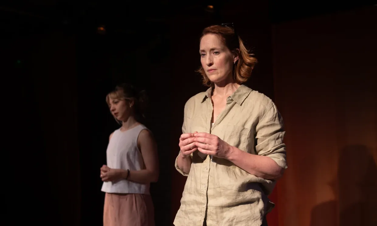 A production still from A Fine Idea. Ella and Georgina stand separately facing the crowd, they both look worried