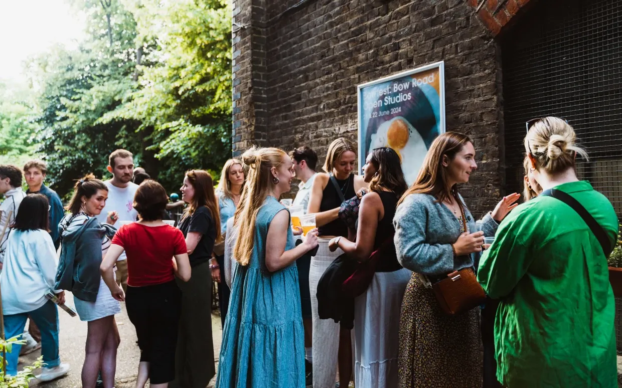 People gather outside Bow Studios, chatting with drinks in their hands.