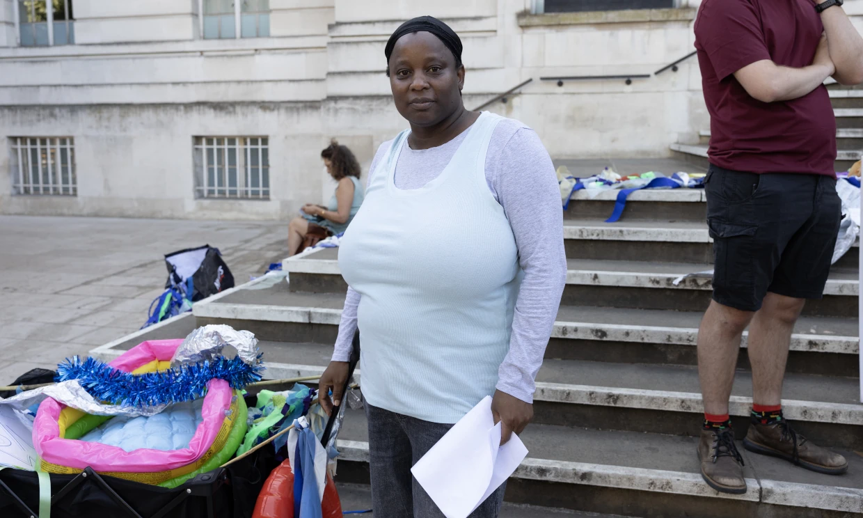 A woman stands at the protest looking to camera.