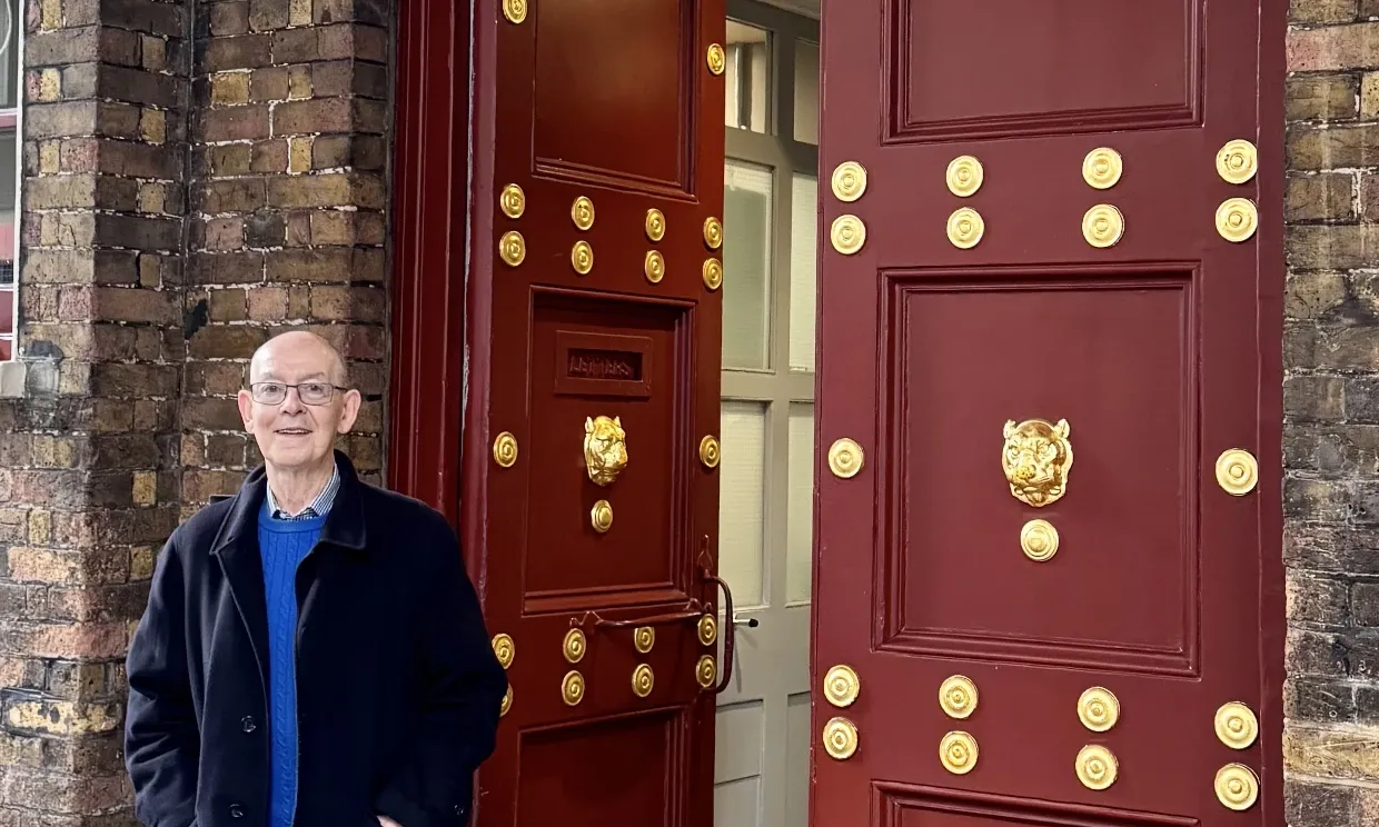 Eden standing outside the large doors of another theatre