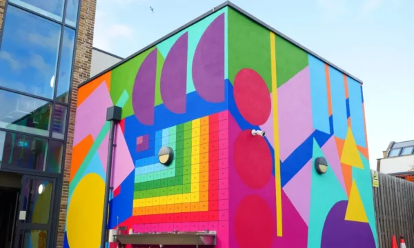 A large colourful mural adorns rectangular sides of a school building.