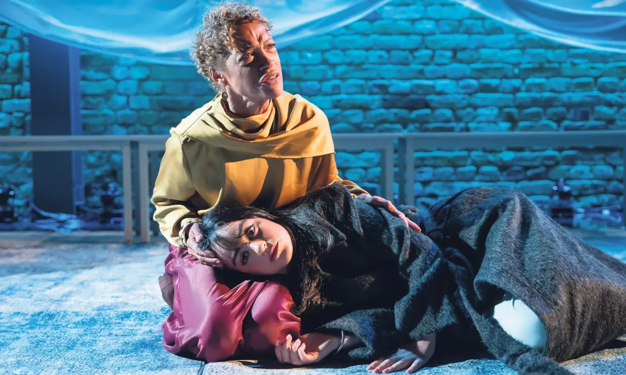 Indra holds Mithra in her lap on stage.