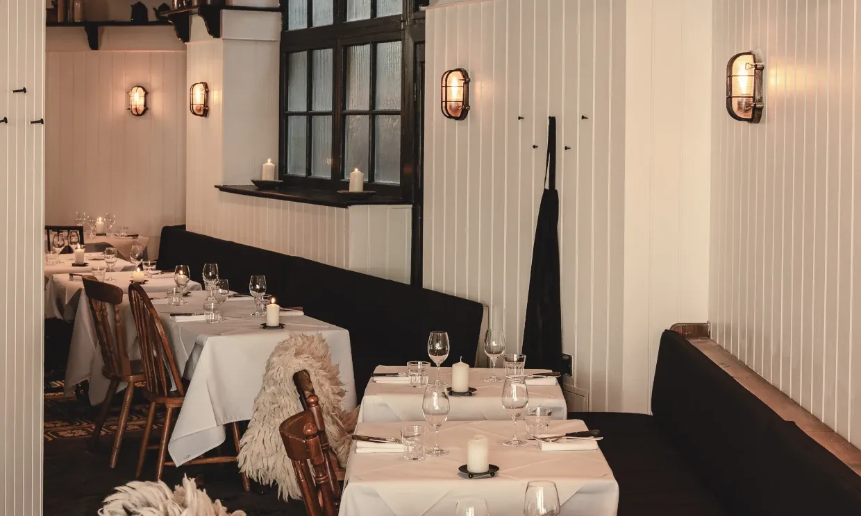 Interior of the restaurant, with a white colour theme and set tables.