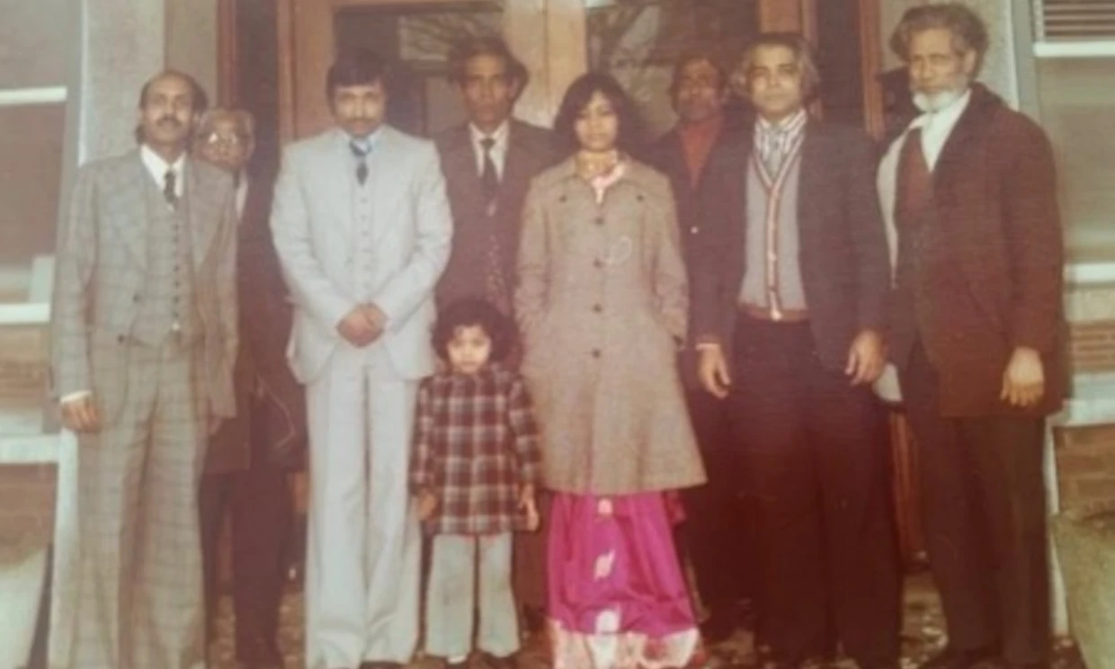 A family picture of the Alis. There are 8 adults and one small child all standing in a row
