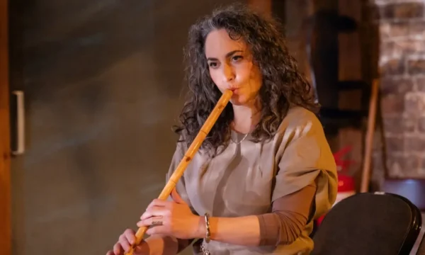 Kalia plays a long wooden flute.