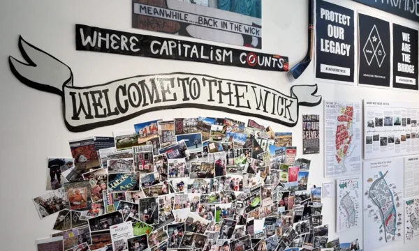 A wall featuring lots of photos. WELCOME TO THE WICK is in a graphic banner, and above that is says WHERE CAPITALISM COUNTS