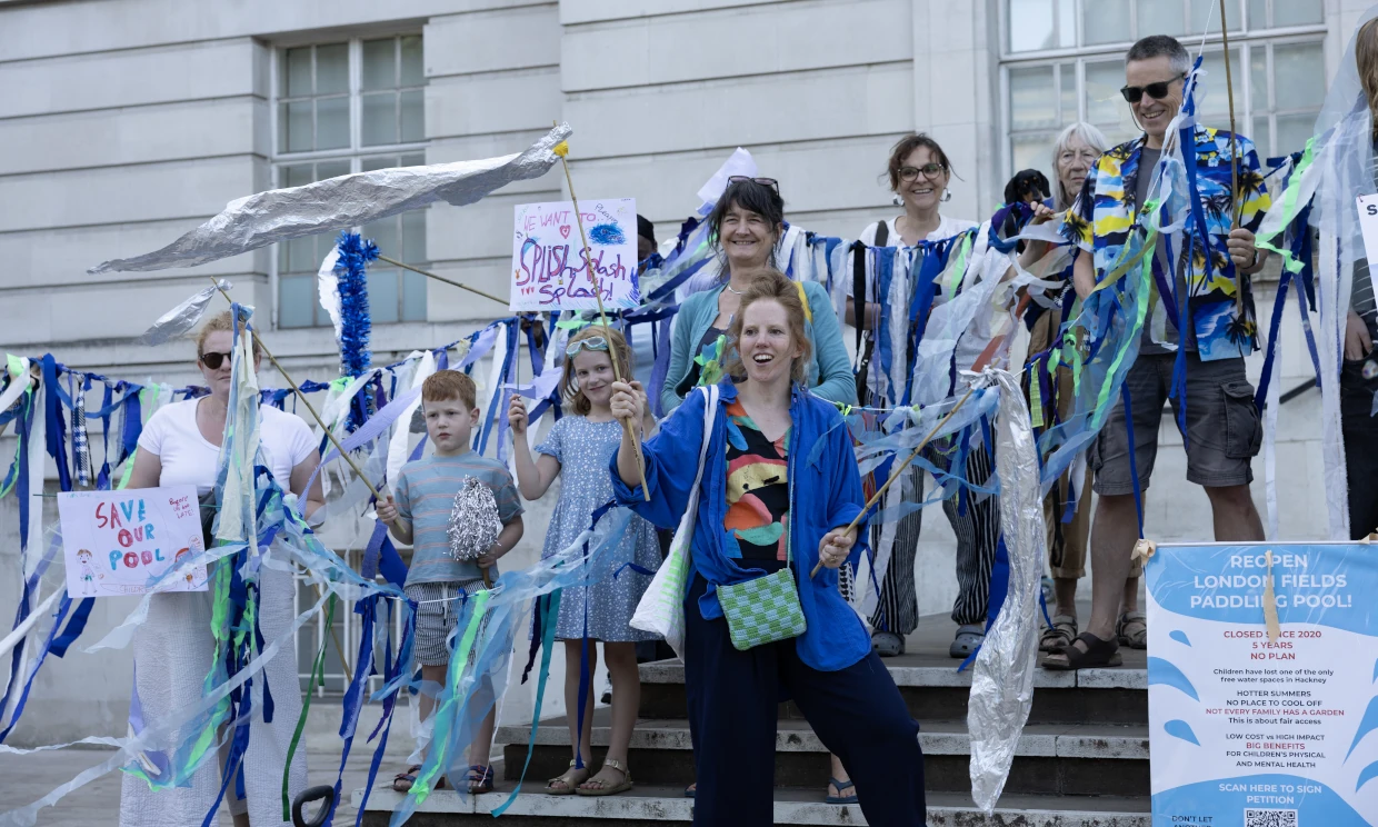 Adults and children protesting together with SAVE OUR POOL.
