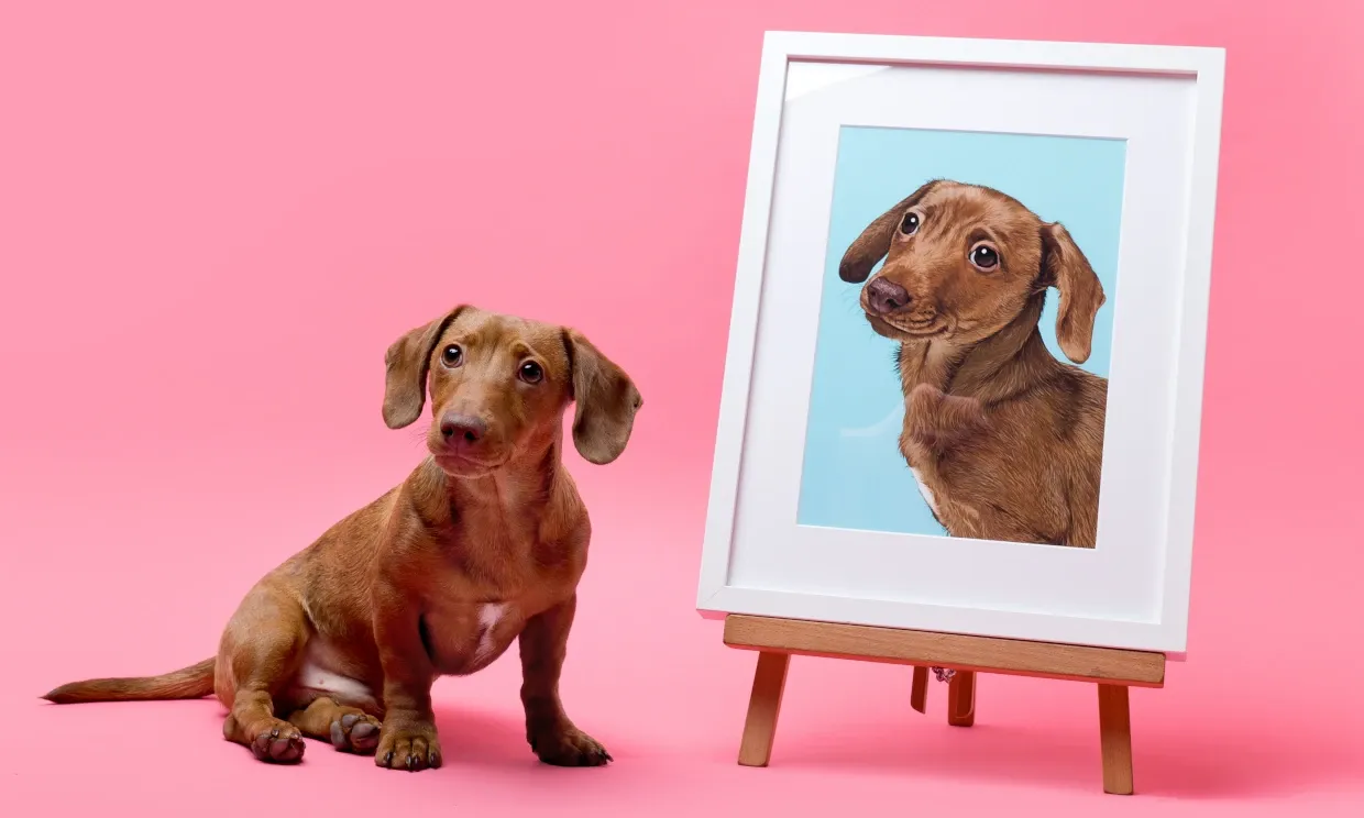 A small sausage dog sits next to a life size portrait of it.