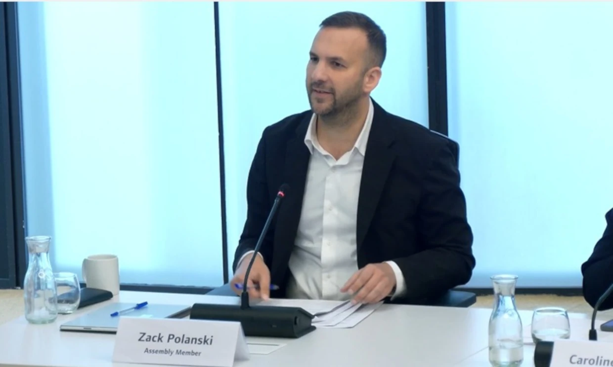 Zack Polanksi sits at a desk talking into a microphone.