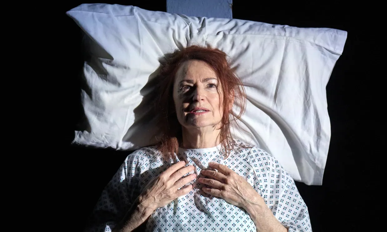 A birds-eye view of a woman lying in bed in what appears to be a hospital gown. She looks frazzled and lost