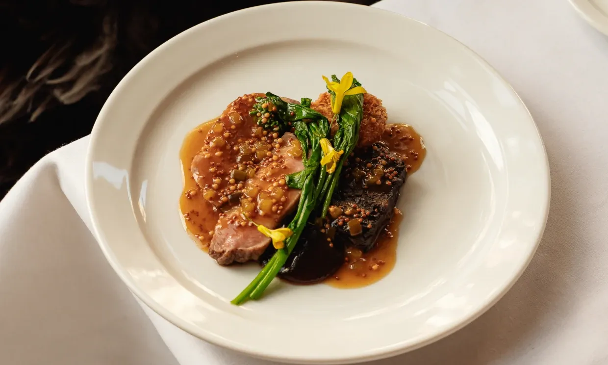 Pork, served with veg, sauce and some little yellow flowers on the top.