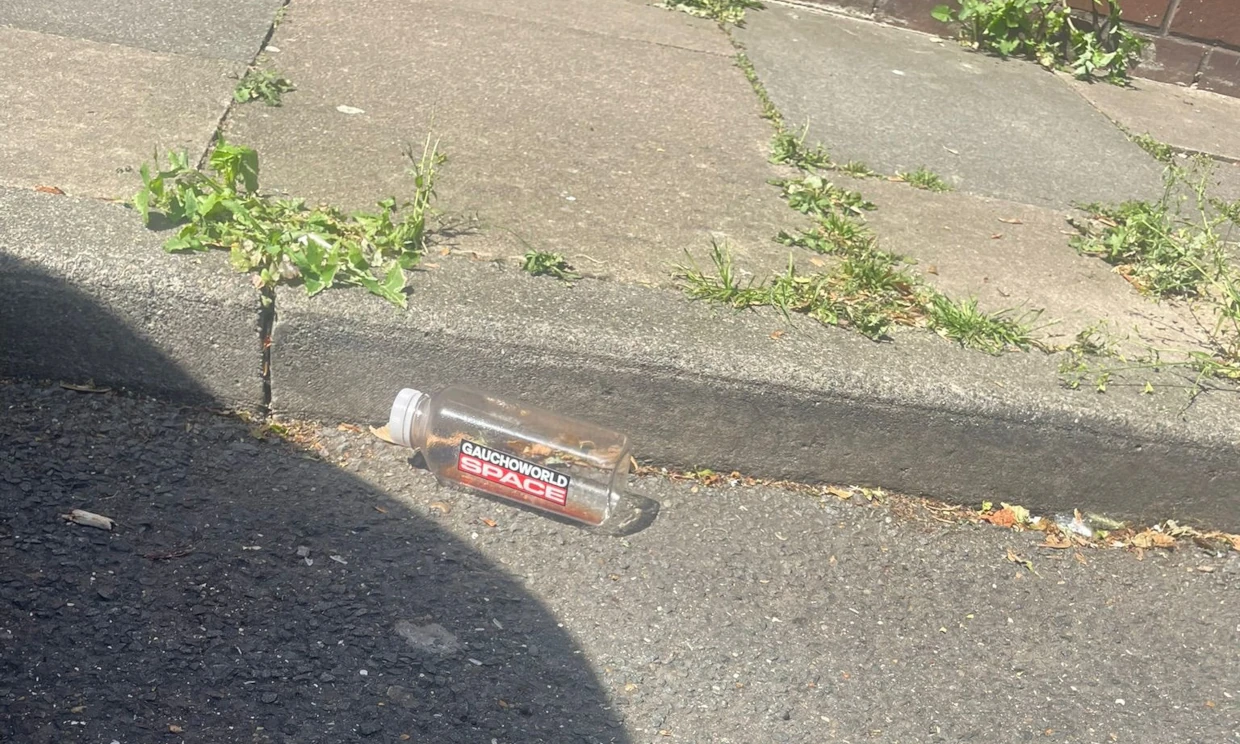 A bottle strewn on the road with the branding Gauchoworld space