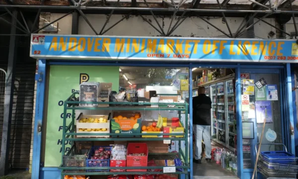 Exterior of "Andover Minimarket Off Licence" - there is fruit outside in boxes and the shop exterior is painted blue