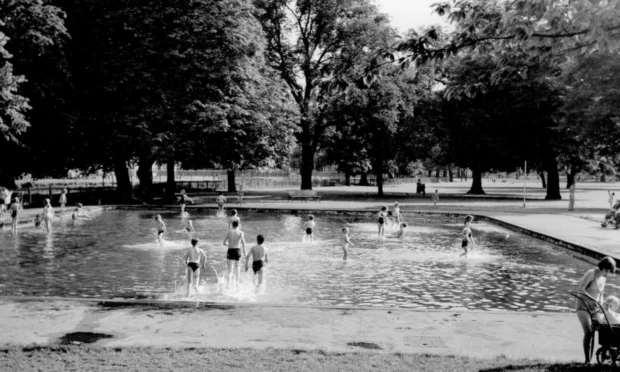 Black and white photo of children playing in large paddling pool.