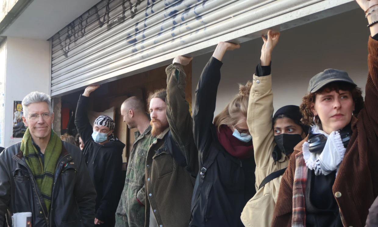 A row of protesters stood below the market shutters, blocking the forced closure of the stand