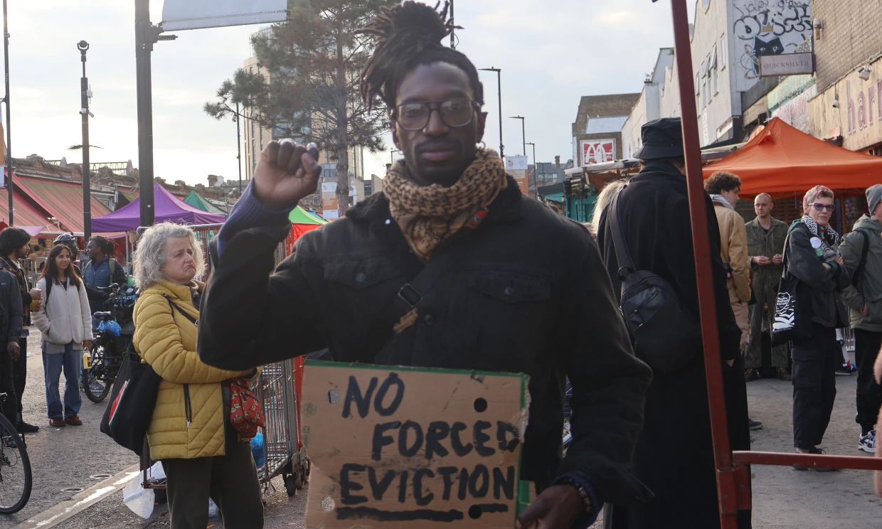 A man stands holding a sign that says "No Forced Eviction".