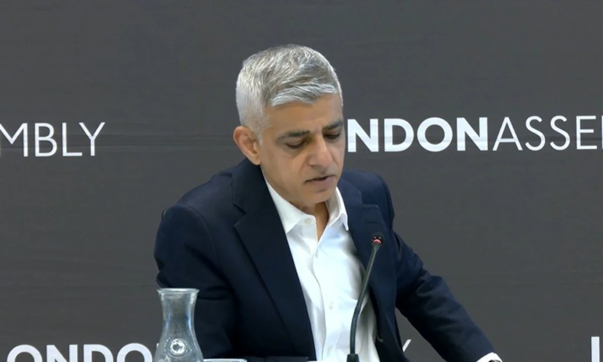 Sadiq Khan sits at a desk with a microphone in front of him